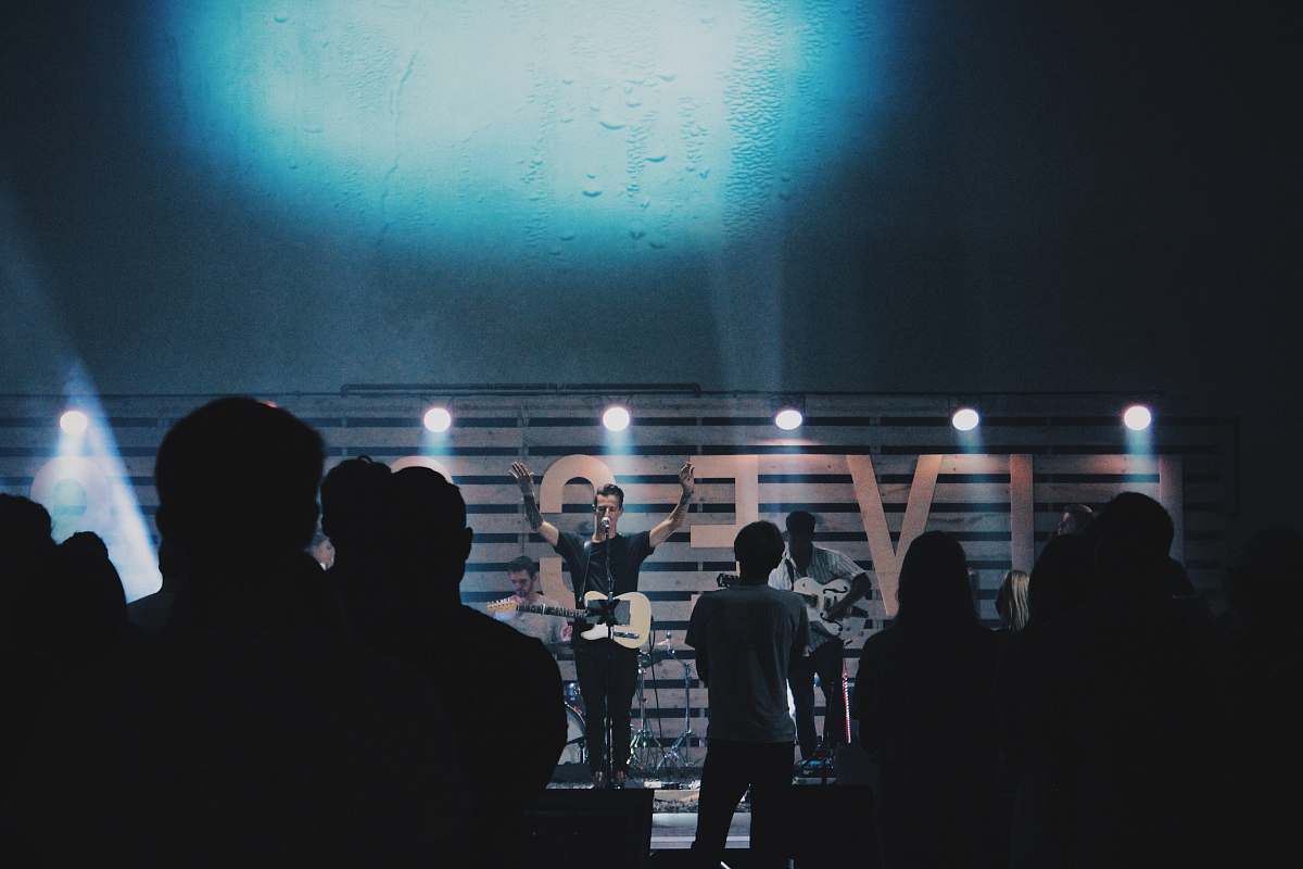 interior design man standing and singing in front of crowded people indoors